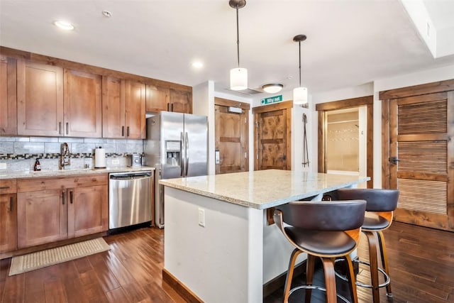 kitchen featuring a kitchen island, stainless steel appliances, dark wood-style floors, and a sink