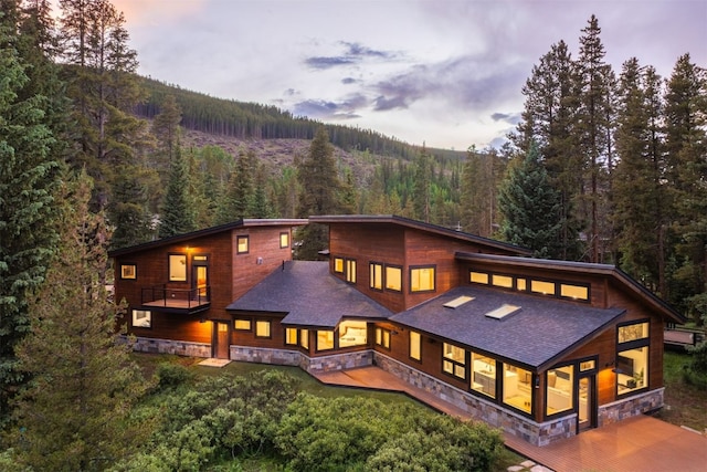 89 Wilderness Dr, Breckenridge, CO 80424 - back of property at dusk with a forest view, stone siding, and a balcony