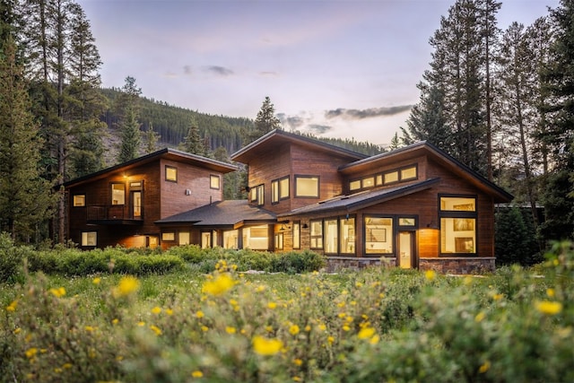 89 Wilderness Dr, Breckenridge, CO 80424 - back of property featuring a balcony, stone siding, and a wooded view
