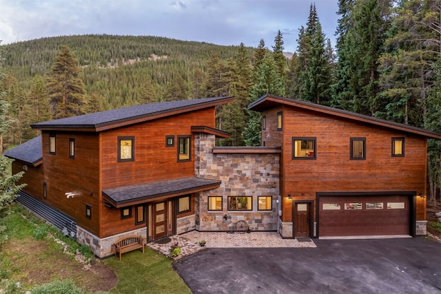 89 Wilderness Dr, Breckenridge, CO 80424 - view of front facade featuring a view of trees, stone siding, an attached garage, driveway, and a porch