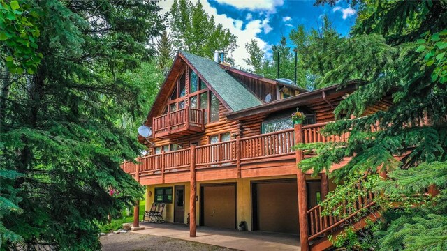 192 Johnson Rd, Silverthorne, CO 80498 - rear view of property with log exterior, a balcony, an attached garage, a patio, and roof with shingles