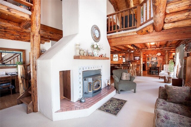 192 Johnson Rd, Silverthorne, CO 80498 - living area with log walls, a wood stove, a high ceiling, beamed ceiling, and carpet floors