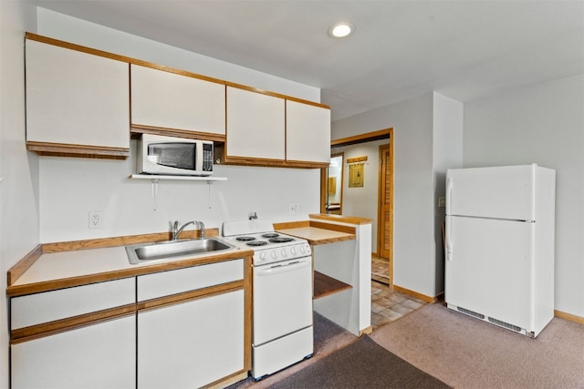 kitchen with white appliances, a sink, light countertops, white cabinets, and light carpet