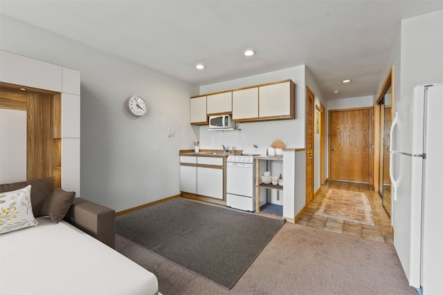 kitchen featuring white appliances, light colored carpet, recessed lighting, white cabinetry, and baseboards