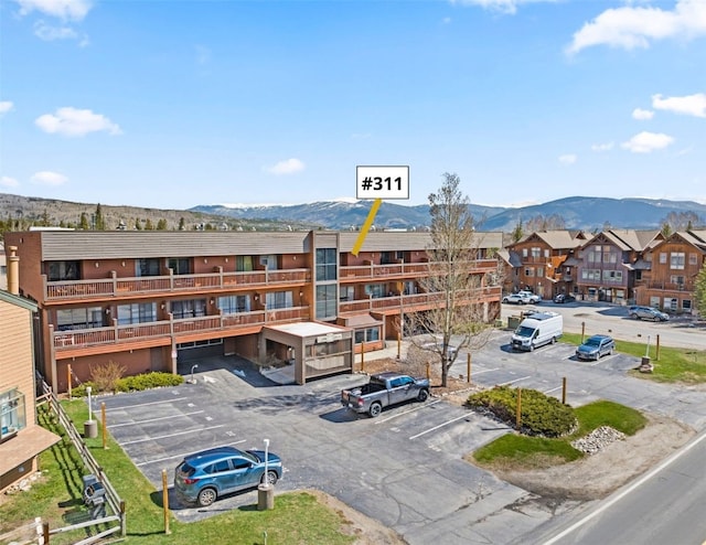 view of building exterior with uncovered parking, a mountain view, and a residential view