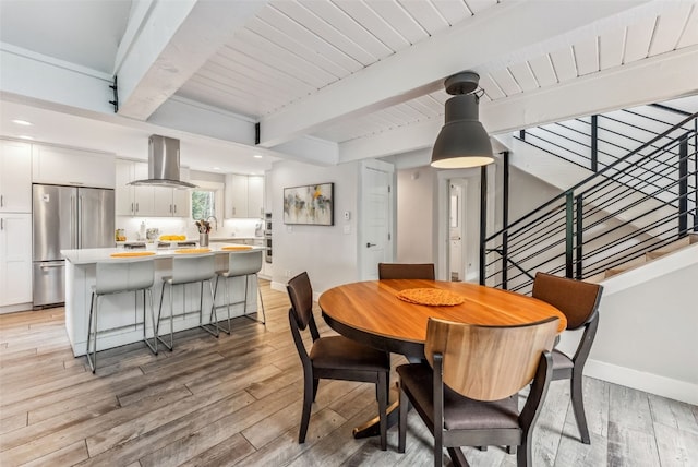 dining area with beam ceiling, light hardwood / wood-style floors, and wooden ceiling