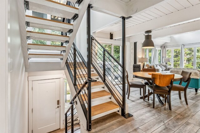 staircase featuring beamed ceiling, wood-type flooring, plenty of natural light, and wooden ceiling