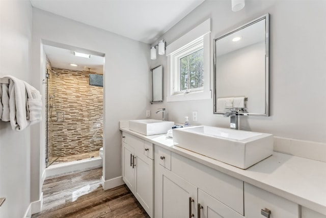 bathroom with hardwood / wood-style floors, vanity, toilet, and walk in shower