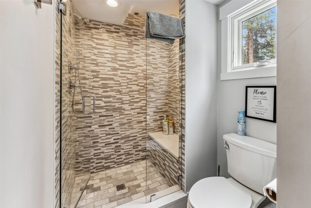 bathroom featuring toilet and a shower with shower door