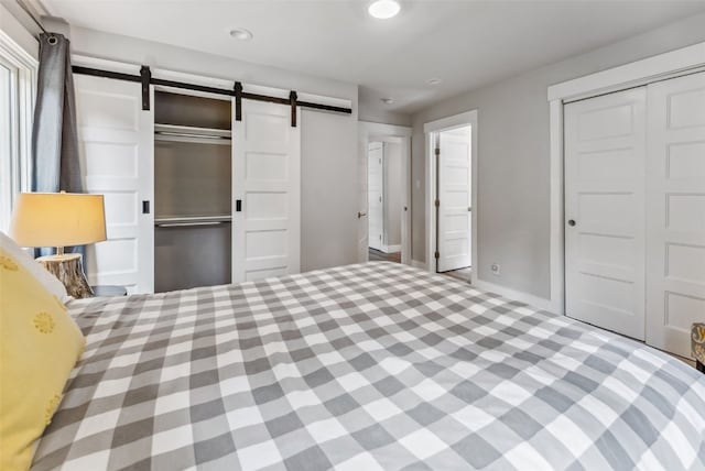 unfurnished bedroom with a barn door and multiple closets