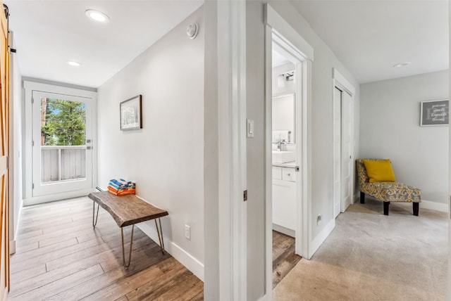 hallway with a barn door and light hardwood / wood-style floors