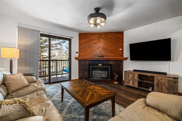 living room with a glass covered fireplace, wood finished floors, and a chandelier