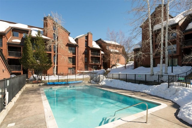 snow covered pool with a community pool and fence