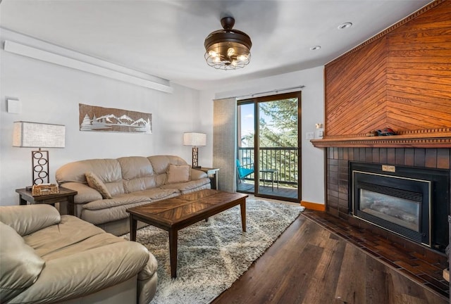 living area with a glass covered fireplace, baseboards, wood finished floors, and recessed lighting