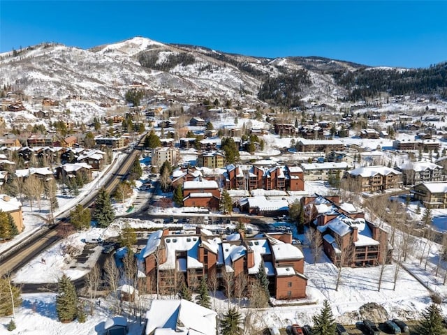 snowy aerial view with a mountain view and a residential view