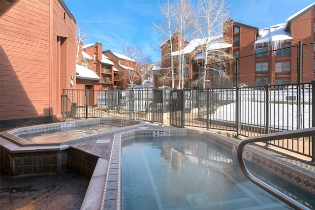 view of pool featuring a community hot tub, a residential view, and fence