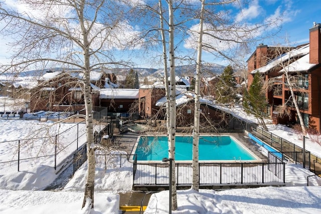 snow covered pool featuring a residential view, a fenced in pool, and fence