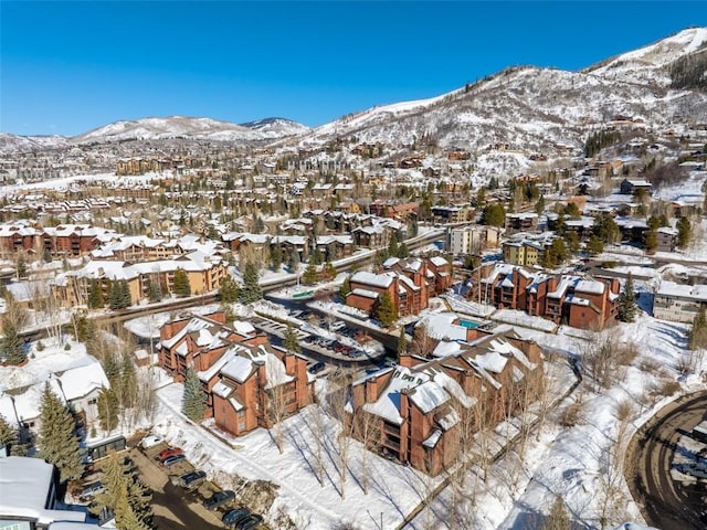 snowy aerial view featuring a residential view and a mountain view