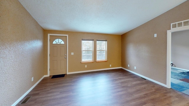 entryway with a textured wall, wood finished floors, visible vents, and baseboards