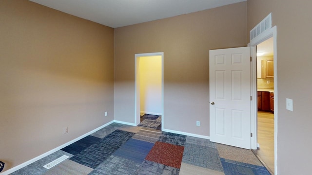 unfurnished room featuring carpet floors, visible vents, and baseboards