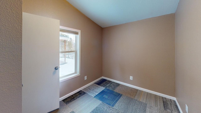 carpeted empty room with vaulted ceiling and baseboards