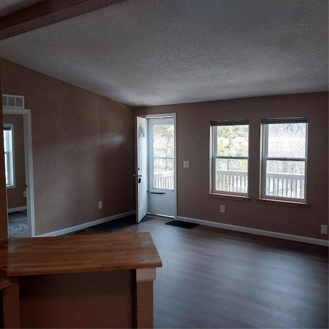 entrance foyer with wood finished floors, a textured ceiling, a textured wall, baseboards, and visible vents