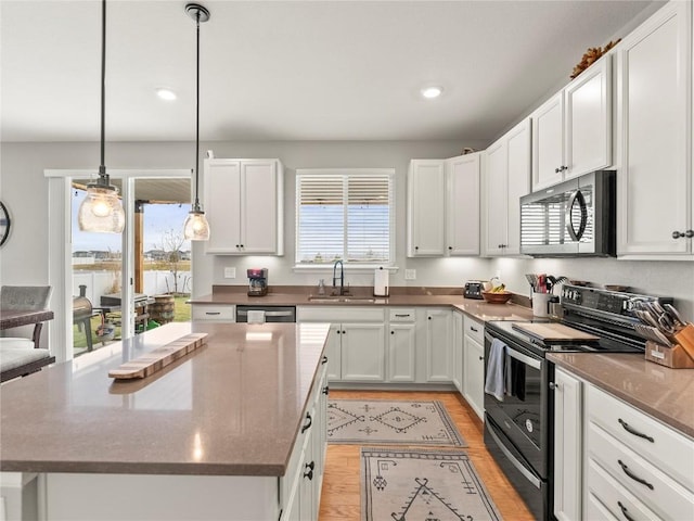 1527 Biffle Ct, Berthoud, CO 80513 - kitchen featuring appliances with stainless steel finishes, a sink, light wood-style flooring, white cabinets, and a kitchen island