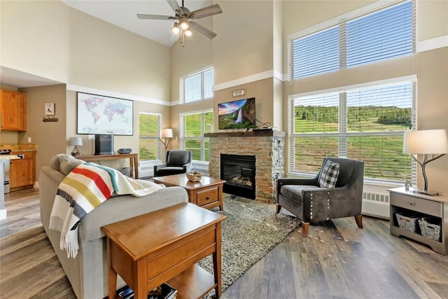 300 Base Camp Cir Unit 405, Granby, CO 80446 - living area featuring a towering ceiling, light wood-type flooring, ceiling fan, a stone fireplace, and radiator heating unit
