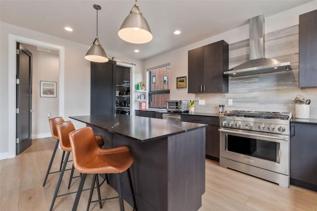2894 Owl Hoot Trl, Steamboat Springs, CO 80487 - kitchen featuring high end stainless steel range oven, wall chimney exhaust hood, dark countertops, a kitchen breakfast bar, and tasteful backsplash