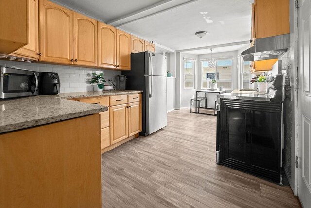 410 Washington St, Craig, CO 81625 - kitchen featuring appliances with stainless steel finishes, tasteful backsplash, light wood finished floors, under cabinet range hood, and light stone counters