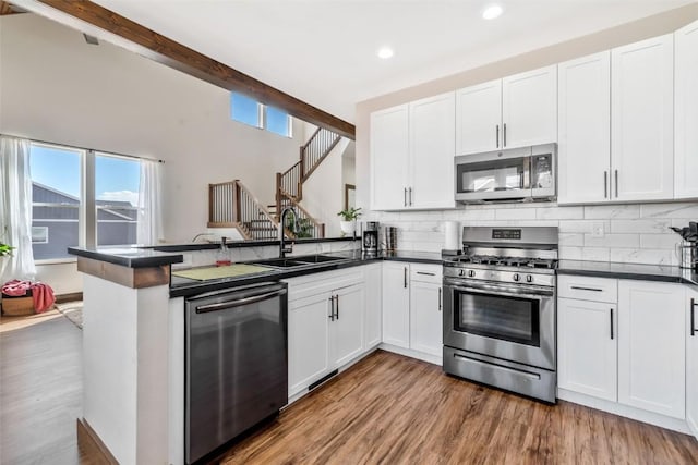 342 Lake View Rd, Hayden, CO 81639 - kitchen with decorative backsplash, a peninsula, dark countertops, a sink, and stainless steel appliances