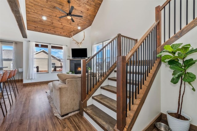 342 Lake View Rd, Hayden, CO 81639 - stairs featuring ceiling fan, wood finished floors, high vaulted ceiling, baseboards, and a warm lit fireplace