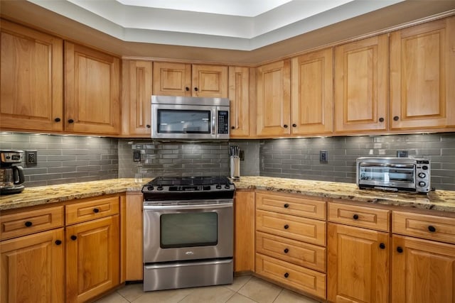 2800 Eagleridge Dr Unit C1, Steamboat Springs, CO 80487 - kitchen featuring appliances with stainless steel finishes, light tile patterned floors, light stone counters, and decorative backsplash