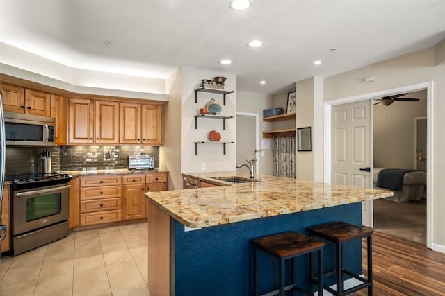 2800 Eagleridge Dr Unit C1, Steamboat Springs, CO 80487 - kitchen with stainless steel appliances, open shelves, a breakfast bar, tasteful backsplash, and light stone counters