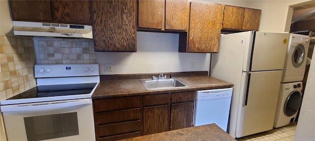 1335 Sparta Plz Unit 7, Steamboat Springs, CO 80487 - kitchen featuring white appliances, under cabinet range hood, stacked washer and clothes dryer, backsplash, and dark countertops