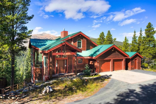 181 Red Fox Ct, Breckenridge, CO 80424 - view of front of property featuring a chimney, a garage, driveway, a mountain view, and metal roof