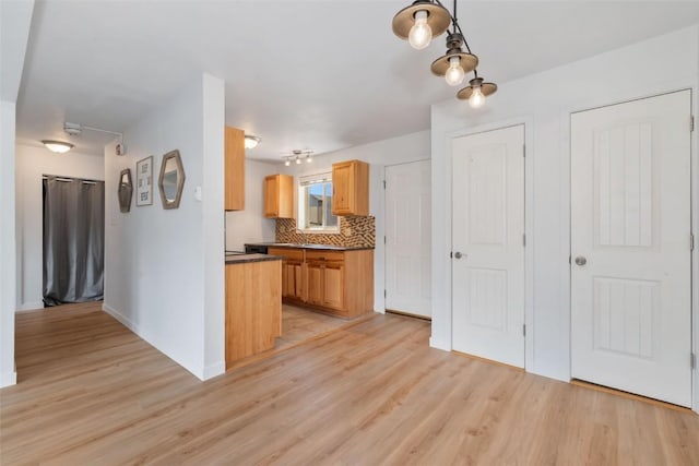 1565 Shadow Run Frontage Unit 103, Steamboat Springs, CO 80487 - kitchen with light wood-type flooring, dark countertops, decorative backsplash, and baseboards