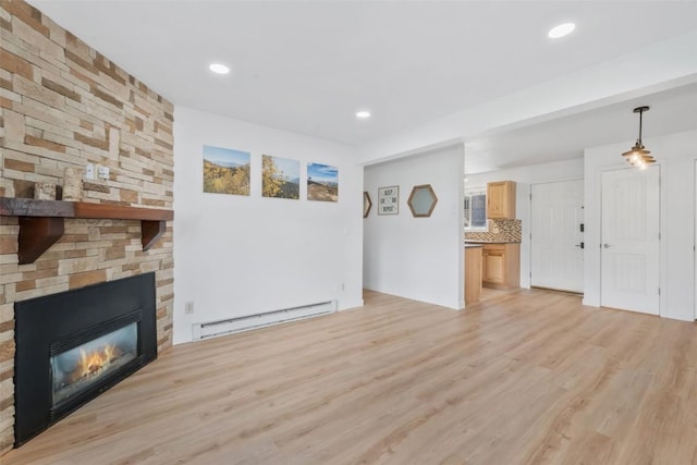 1565 Shadow Run Frontage Unit 103, Steamboat Springs, CO 80487 - unfurnished living room featuring baseboard heating, light wood-style flooring, a stone fireplace, and recessed lighting