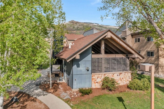 1565 Shadow Run Frontage Unit 103, Steamboat Springs, CO 80487 - view of front facade featuring a chimney, stone siding, a mountain view, and roof with shingles