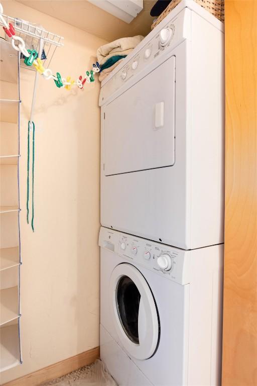 washroom featuring baseboards, stacked washer and dryer, and laundry area