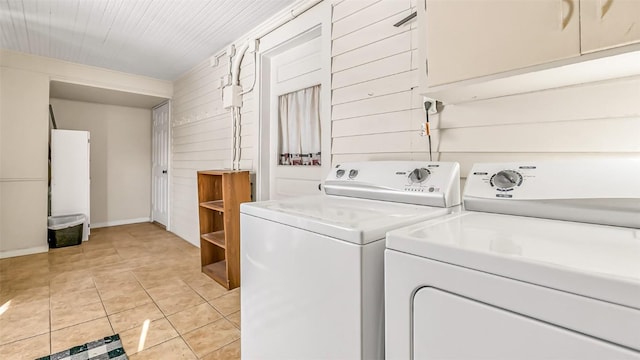 laundry room featuring laundry area, wooden walls, light tile patterned floors, baseboards, and washer and dryer