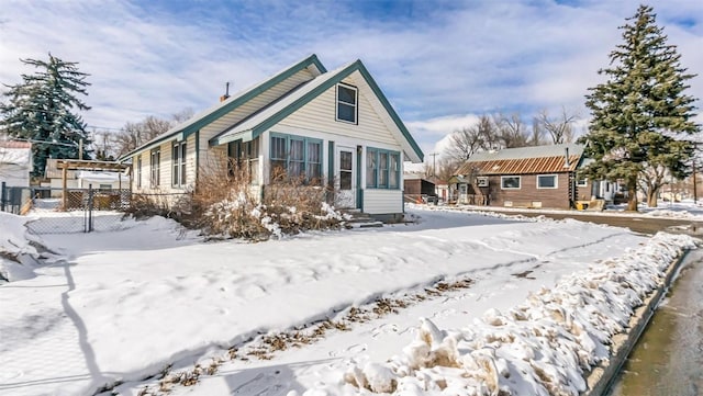 snow covered house featuring fence