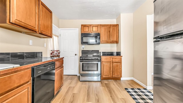 kitchen featuring light wood-type flooring, brown cabinets, and black appliances
