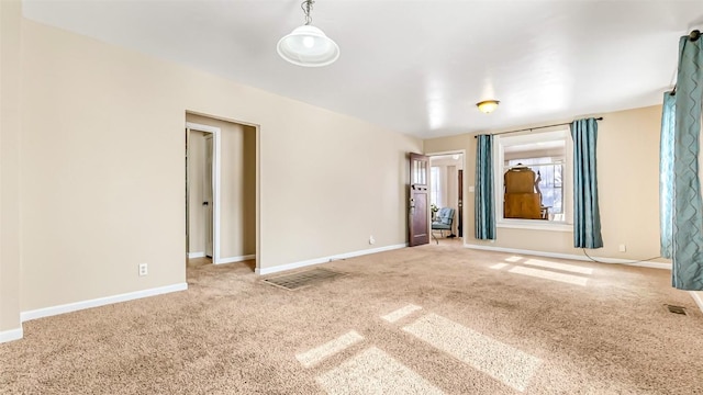 carpeted spare room featuring baseboards and visible vents