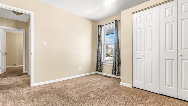 unfurnished bedroom with carpet floors, a closet, baseboards, and visible vents