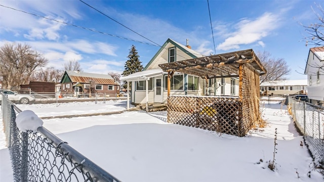 snow covered house featuring fence, a pergola, and entry steps