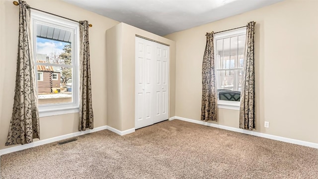unfurnished bedroom featuring a closet, carpet flooring, baseboards, and visible vents