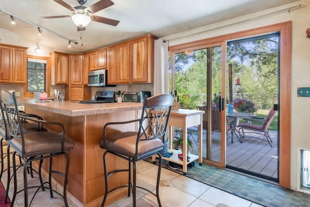27125 Moonlight Way, Steamboat Springs, CO 80487 - kitchen with stainless steel microwave, track lighting, range, ceiling fan, and light tile patterned flooring
