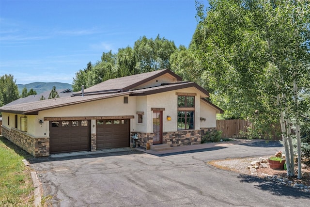 27125 Moonlight Way, Steamboat Springs, CO 80487 - view of front of property with stone siding, stucco siding, a garage, driveway, and a mountain view
