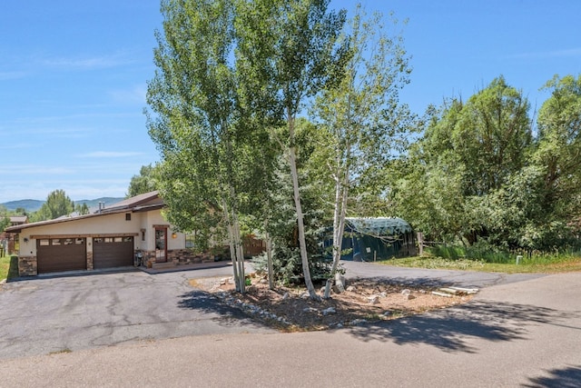 27125 Moonlight Way, Steamboat Springs, CO 80487 - obstructed view of property featuring a garage, driveway, stone siding, and stucco siding